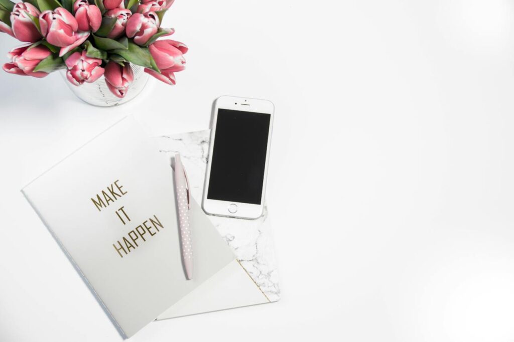 a book cover that says make it happen and a pen on top of it with an phone beside it: how to get motivated 